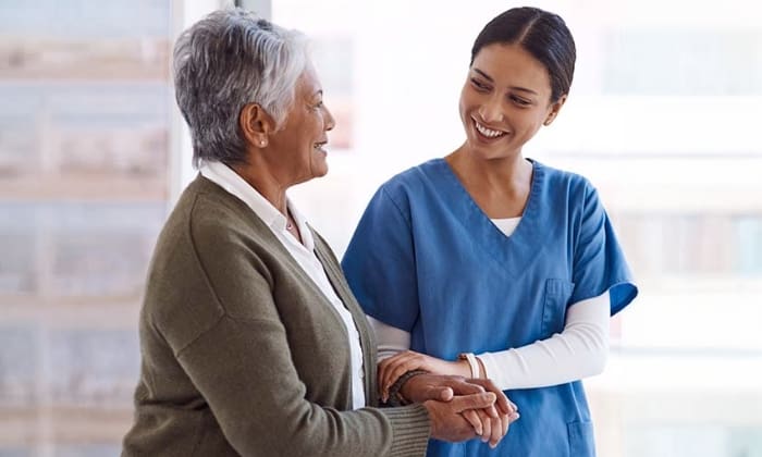 Healthcare professional and senior patient greeting each other.